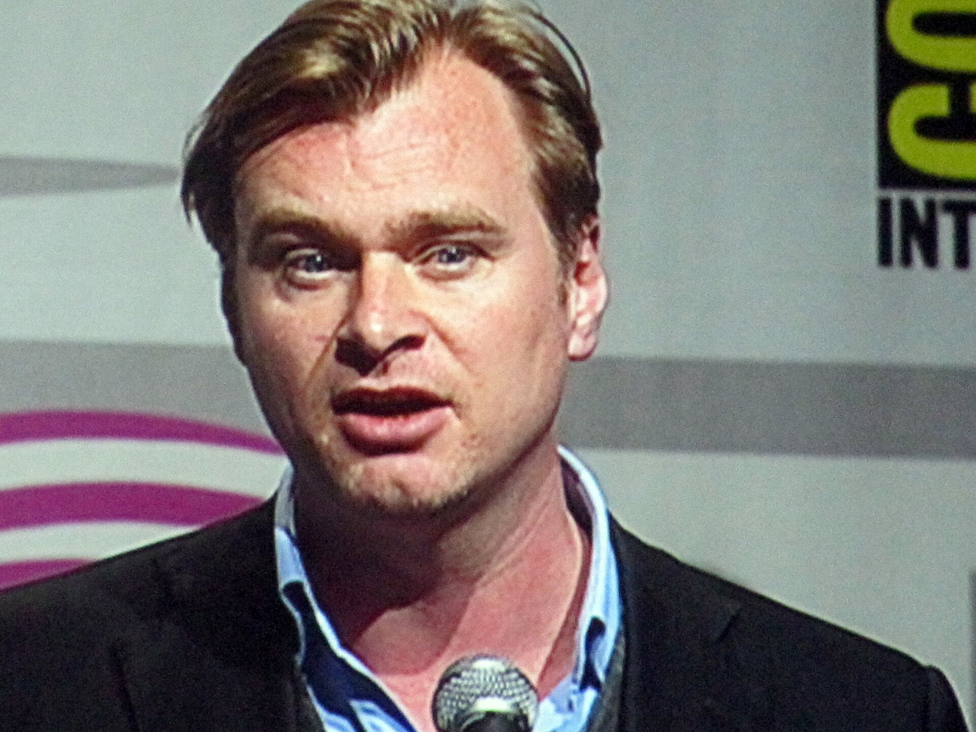 Christopher Nolan directing on set, with The Dark Knight, Oppenheimer and Inception referenced in a ranked filmography